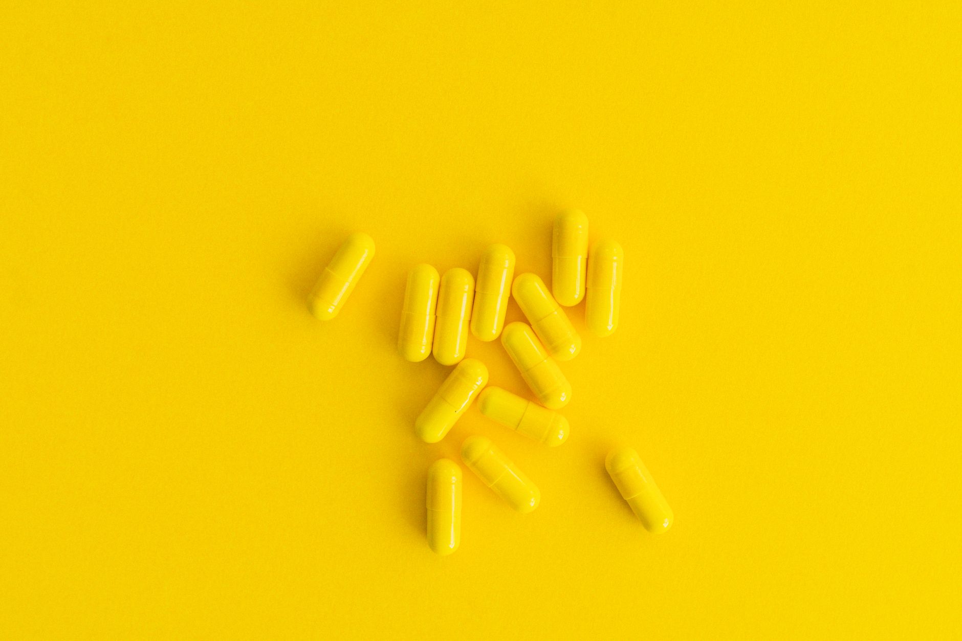 Cluster of yellow capsules on a vibrant yellow background, minimalistic style.