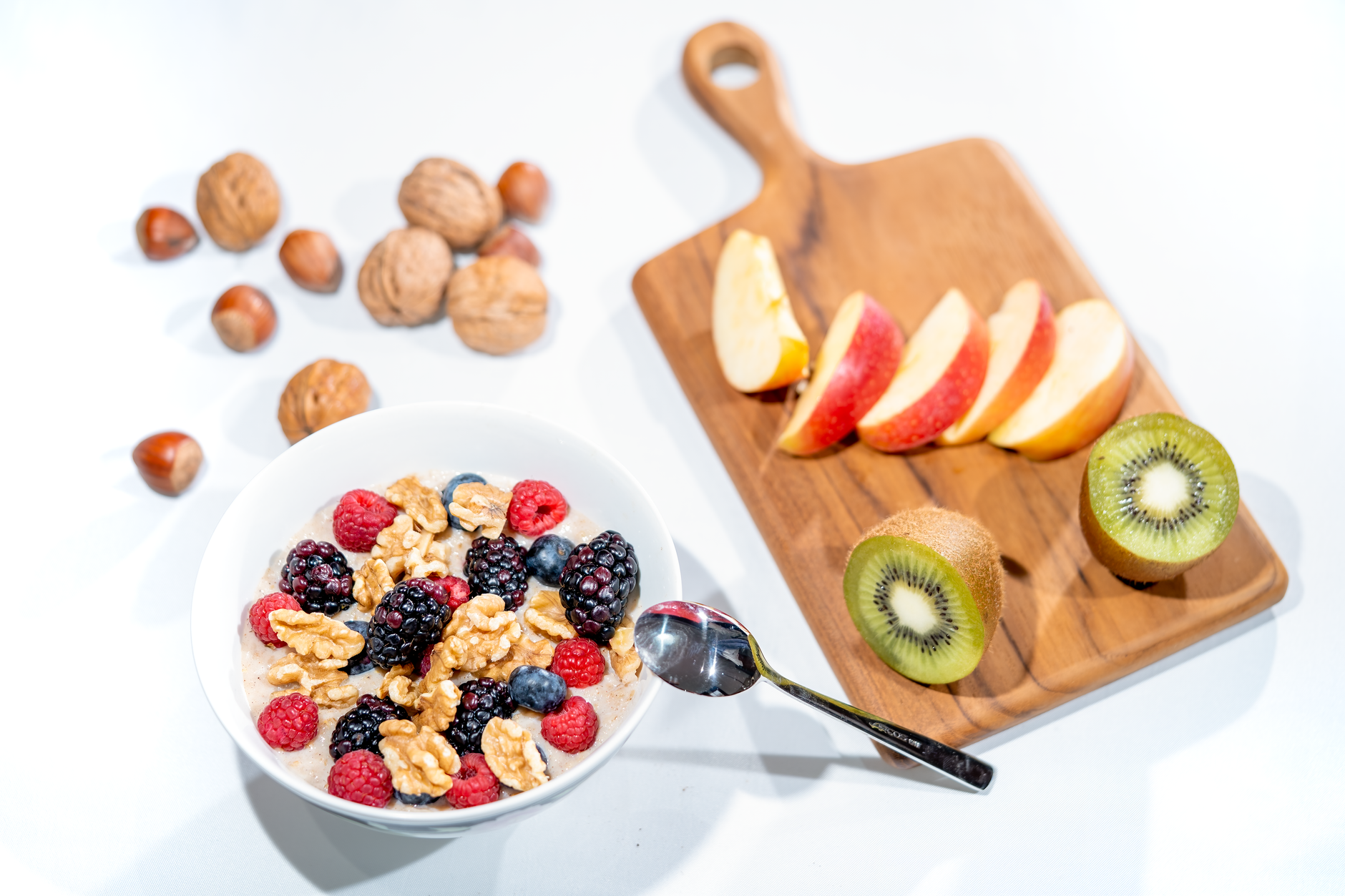 A nutritious breakfast bowl featuring fresh berries and walnuts, served with sliced fruit and kiwi.