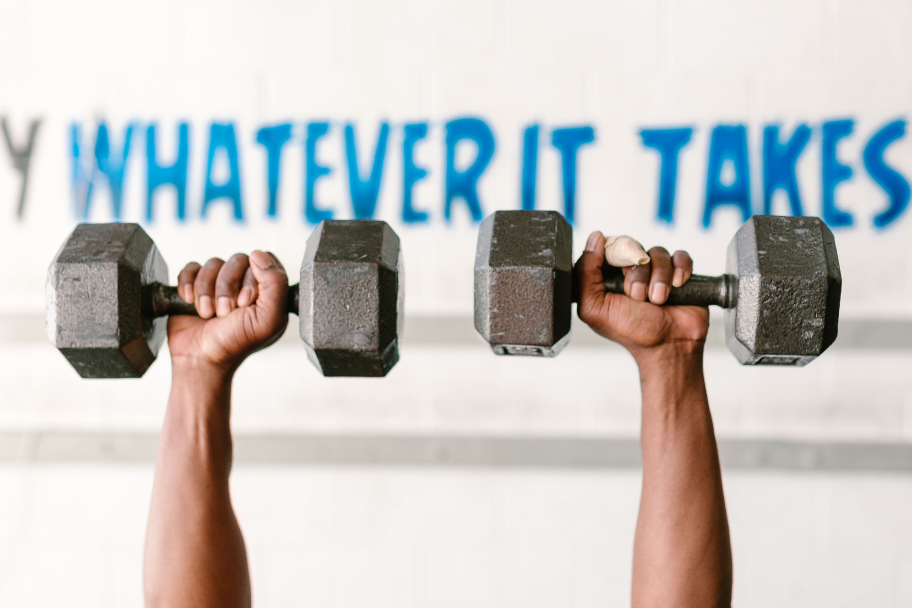 Hands holding dumbbells against motivational text 